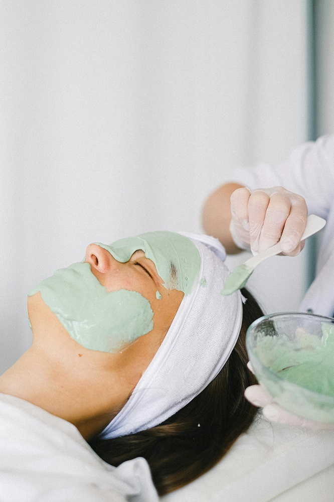 Woman at a spa getting a facial peel mask put on.